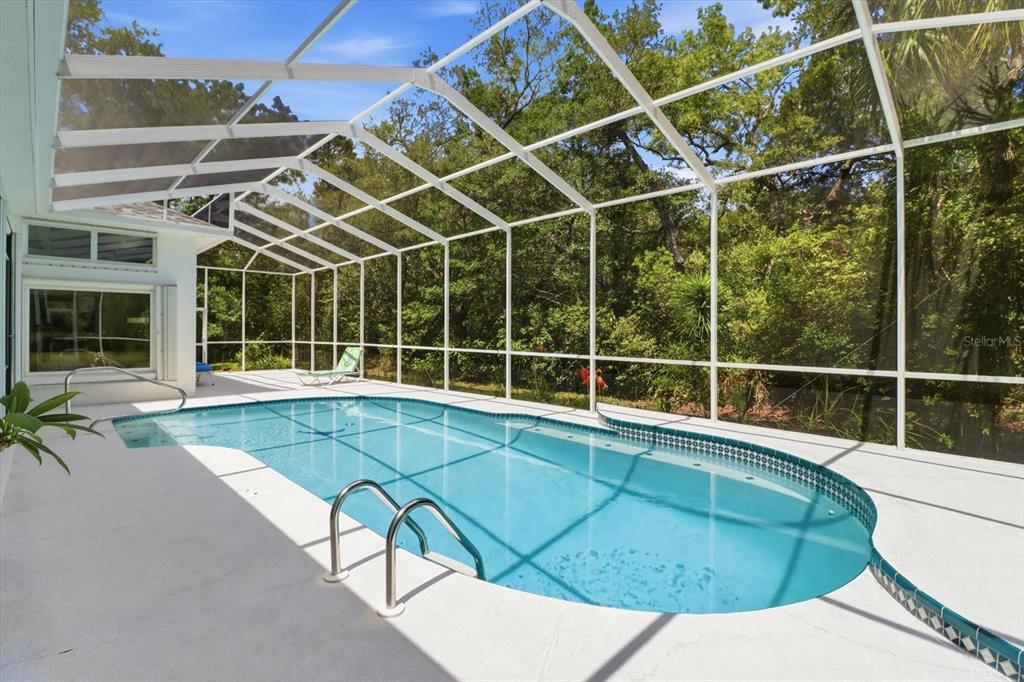 A white house exterior features a three-car garage, a concrete driveway, and a palm tree — 21 FIDDLEWOOD COURT, HOMOSASSA, FL