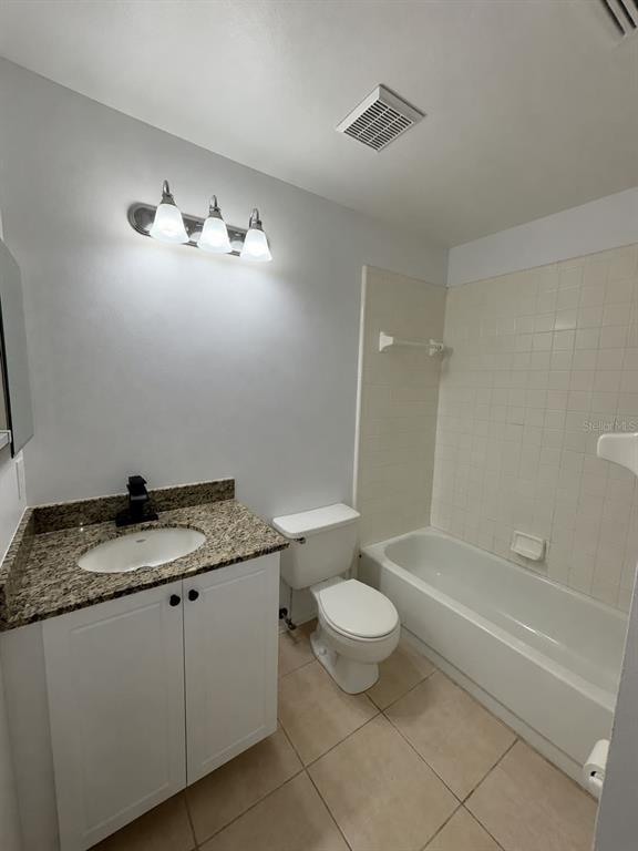 A bathroom features a white vanity with a granite countertop, a toilet, and a tiled tub — 14307 ISLAND COVE DRIVE, ORLANDO, FL