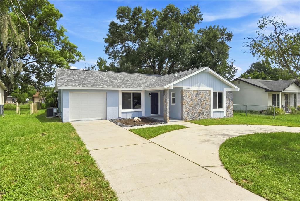 A light blue single-story house with a stone facade, a garage, and a concrete driveway — 7033 WENTWORTH WAY, NEW PORT RICHEY, FL