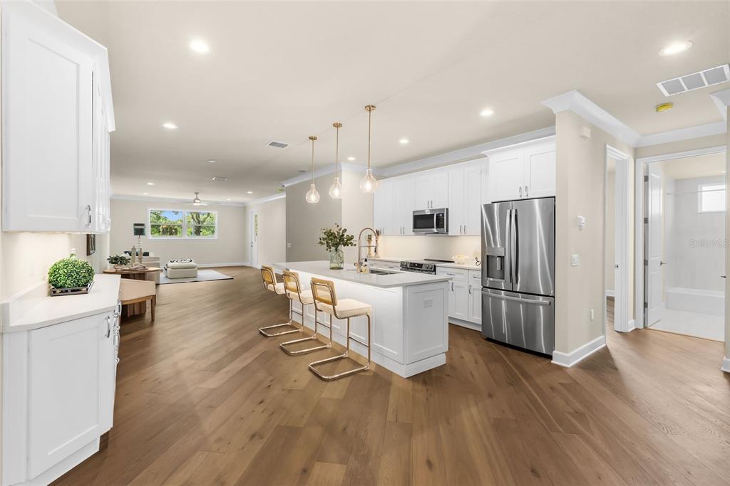 A modern kitchen with white cabinets, a central island, and wood flooring in an open layout — 207 ATHENIAN WAY, TARPON SPRINGS, FL