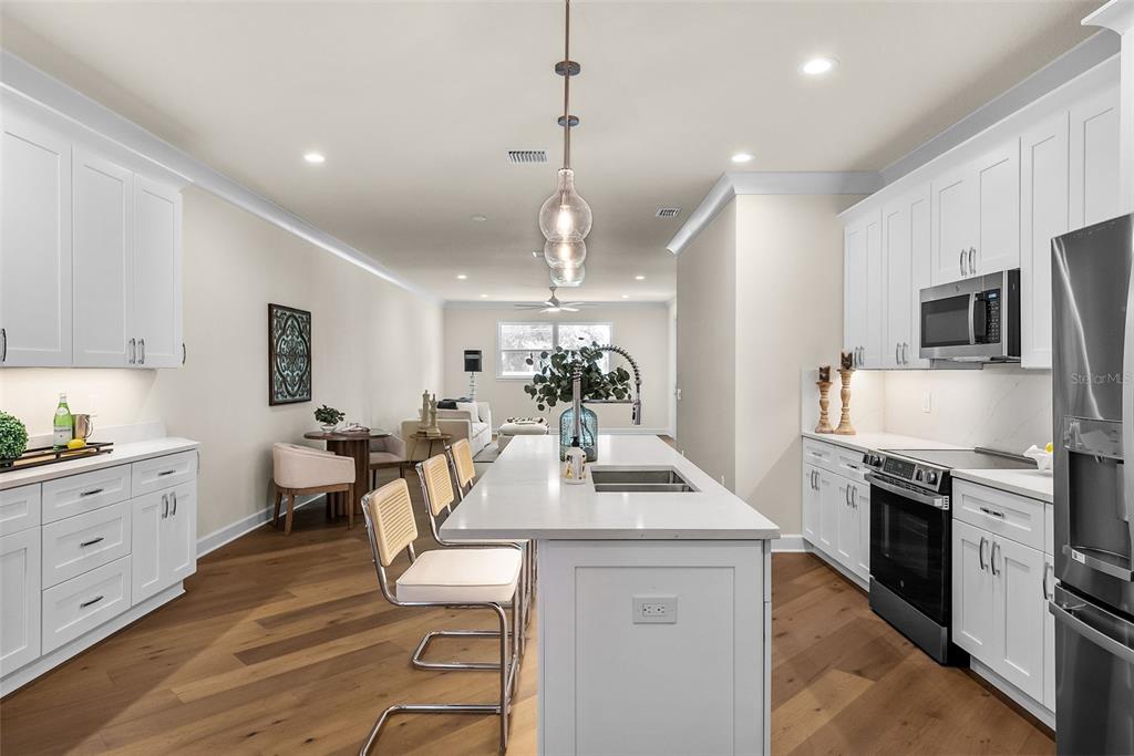 A kitchen with white cabinets, a central island with bar seating, and hardwood flooring — 207 ATHENIAN WAY, TARPON SPRINGS, FL