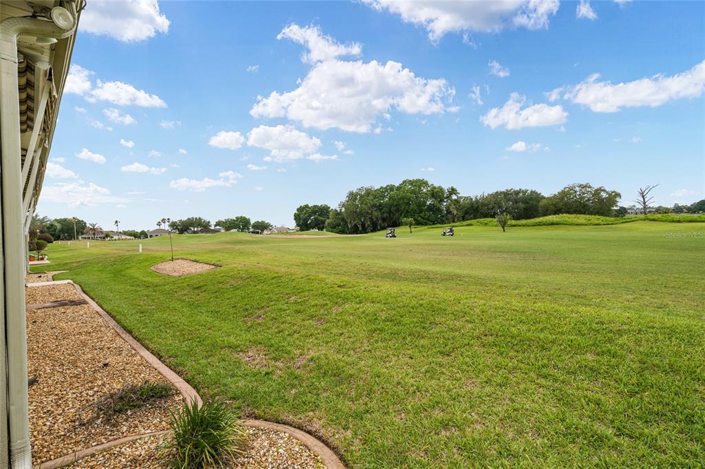 A sunroom features a dining set, lounge chairs, a ceiling fan, and large windows — 13500 SE 97TH TERRACE ROAD, SUMMERFIELD, FL