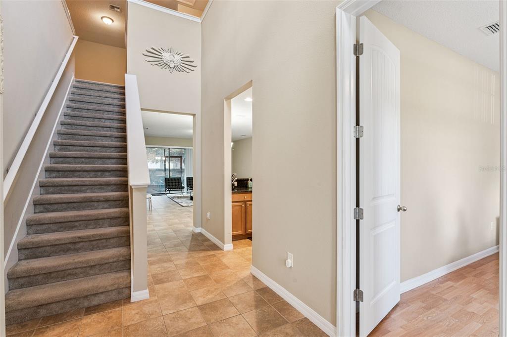 A foyer with a carpeted staircase, tile flooring, and an open doorway leading to a room — 13232 LONGACRE DRIVE, WINDERMERE, FL