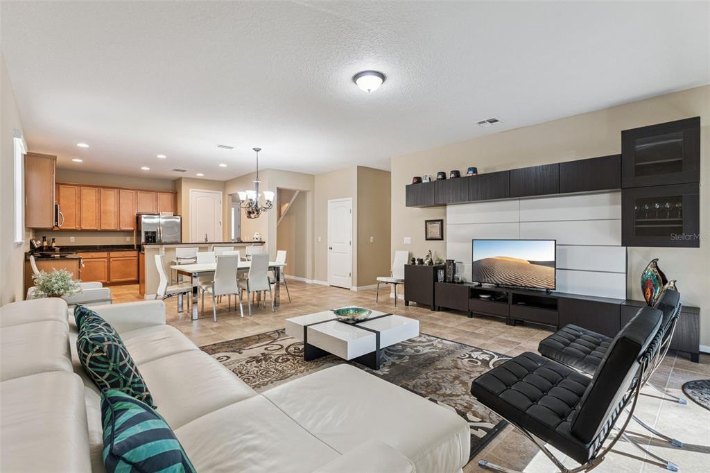 A living room with a white sectional sofa, black chairs, and an open-concept kitchen — 13232 LONGACRE DRIVE, WINDERMERE, FL