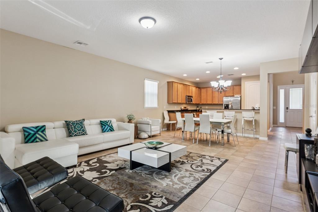 An open-concept living and dining area features tile flooring, a white sectional, and wood cabinets — 13232 LONGACRE DRIVE, WINDERMERE, FL