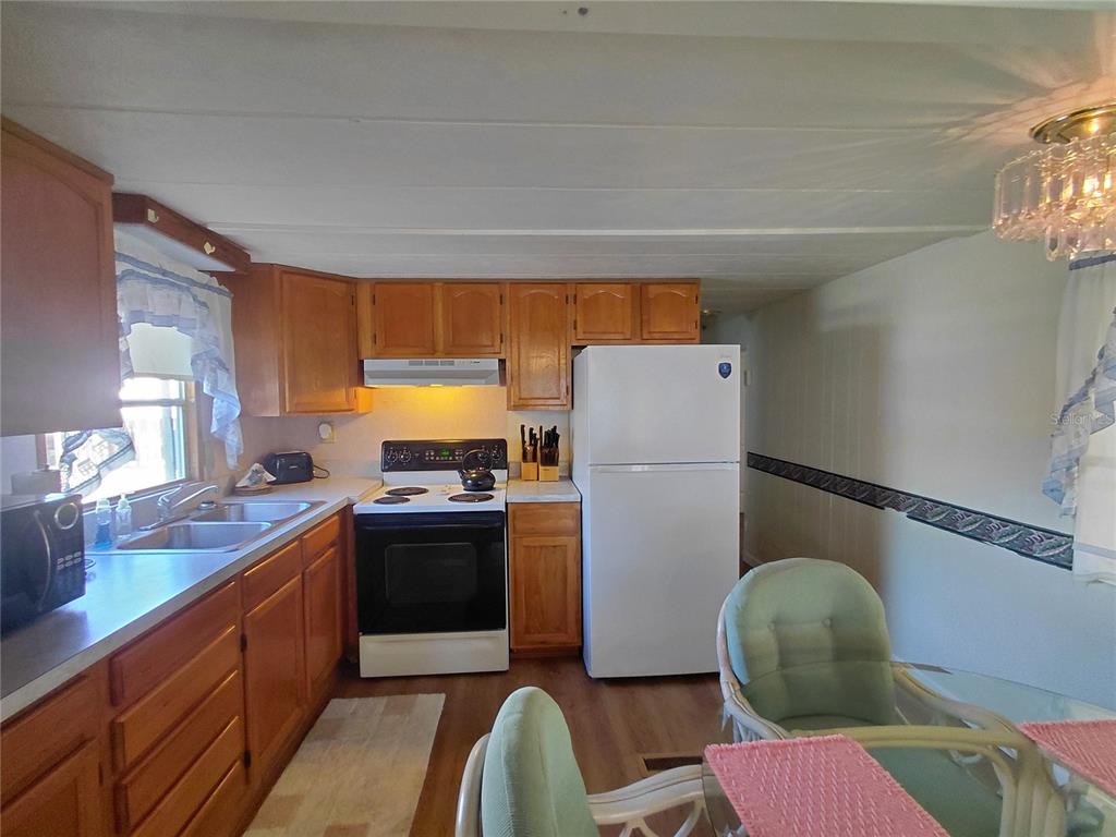 A kitchen features wood cabinets, white appliances, a double sink, and a dining area — 10399 67TH AVENUE UNIT #135, SEMINOLE, FL