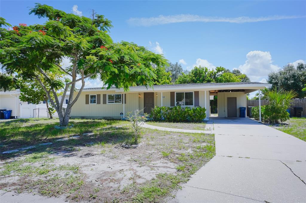 A single-story house with a carport, light-colored siding, and a large tree in the yard — 6515 3RD STREET COURT W, BRADENTON, FL