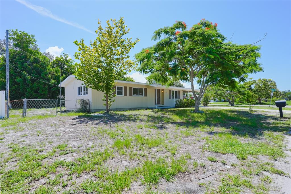 A light-colored, single-story house with a chain-link fence in the yard under a blue sky — 6515 3RD STREET COURT W, BRADENTON, FL