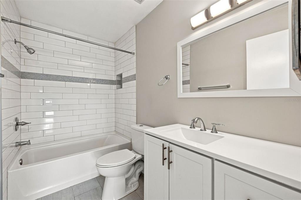 A bathroom features a white vanity, a toilet, and a bathtub with white subway tile — 11409 8TH STREET N UNIT 1504, ST PETERSBURG, FL