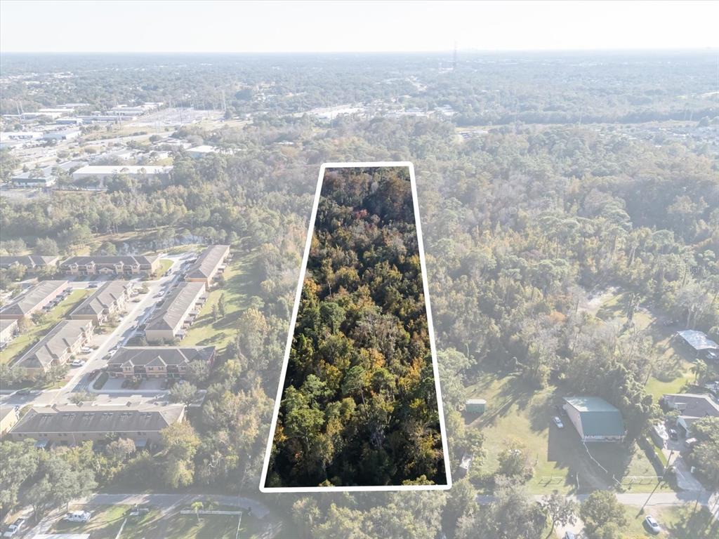 An aerial view shows a trapezoidal plot of wooded land adjacent to a residential complex — HILL TOP DRIVE, LAKE MARY, FL