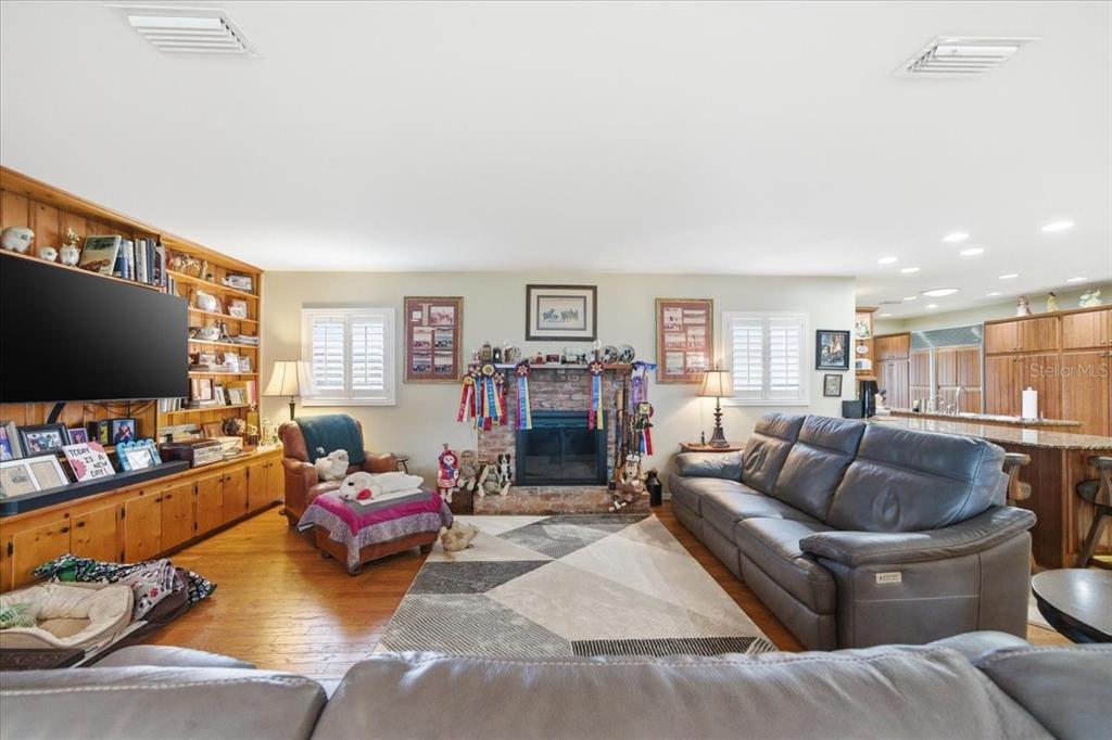 A living room features a brick fireplace, built-in wooden shelving, and a leather sofa — 9449 ROBERTS ROAD, ODESSA, FL