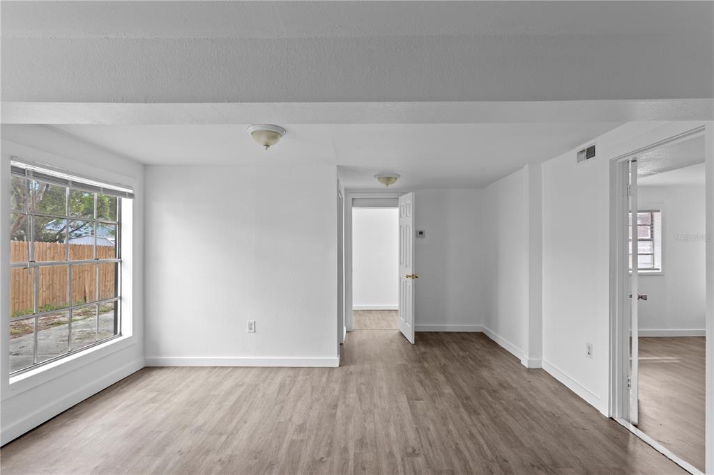 An empty room with white walls, wood-look flooring, and a large window facing a fence — 4103 N HOWARD AVENUE, TAMPA, FL
