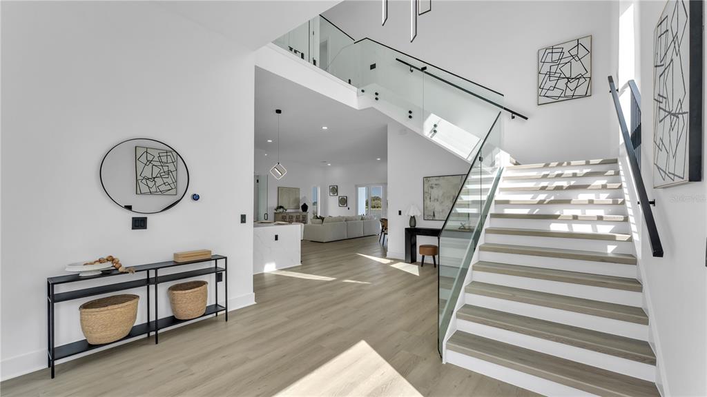 A bright entryway features a modern glass-railed staircase, wood-look flooring, and a children's play area — 156 CALADIUM AVENUE, LAKE ALFRED, FL