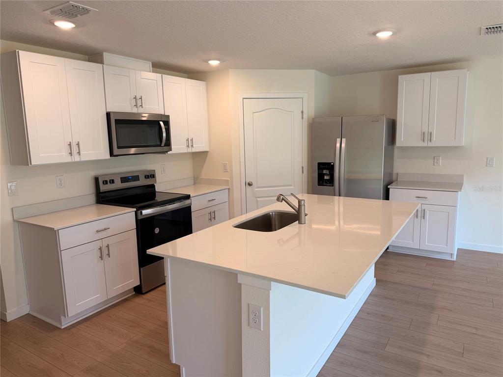 An entryway with wood-look flooring, a glass-paneled front door, and an adjacent office room — 1472 MORNING WALK DRIVE, ORMOND BEACH, FL
