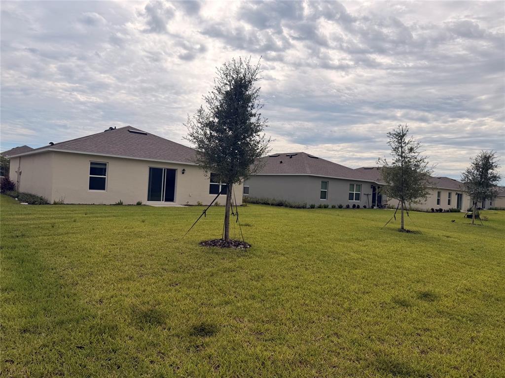 A modern kitchen features white cabinetry, stainless steel appliances, a center island, and wood flooring — 1472 MORNING WALK DRIVE, ORMOND BEACH, FL