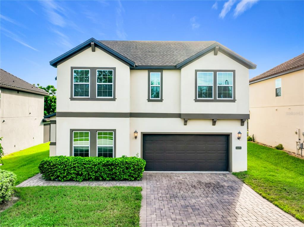 A two-story house with a beige stucco exterior, a dark garage door, and a paved driveway — 2471 SKY STONE COURT, OAKLAND, FL