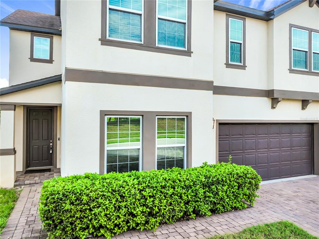 The exterior of a two-story house features a brown garage door, front door, and hedge — 2471 SKY STONE COURT, OAKLAND, FL