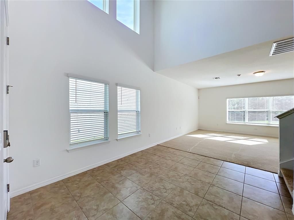 An interior view shows a room with tiled flooring, carpeted area, and high vaulted ceilings — 2471 SKY STONE COURT, OAKLAND, FL