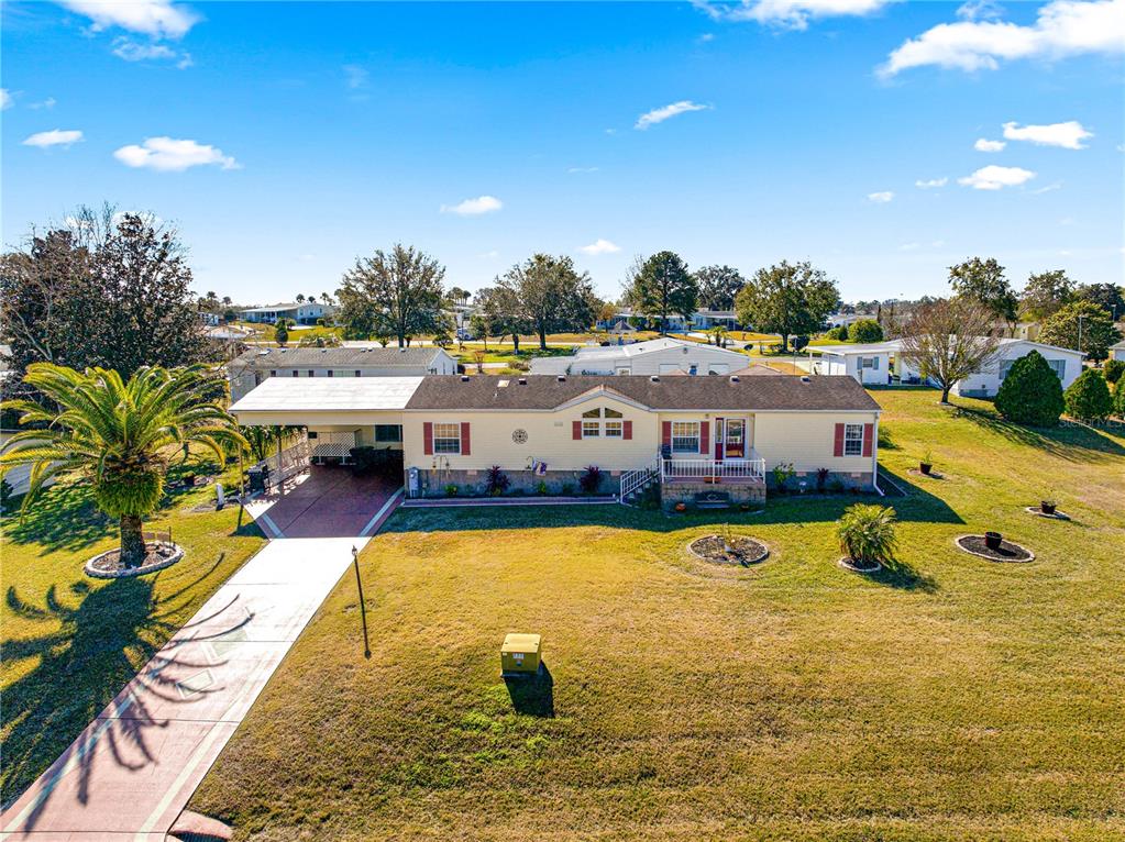 A yellow house exterior features a covered patio, a white railing, and a glass door — 9630 SE 165TH LANE, SUMMERFIELD, FL