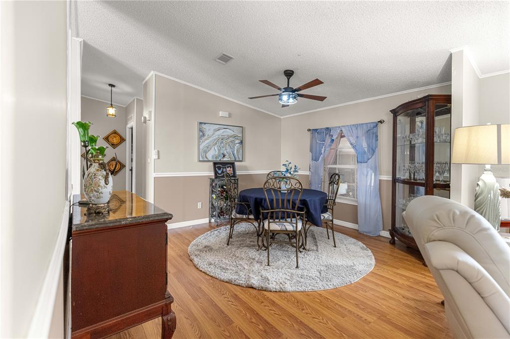 A living room features a fireplace, vaulted ceiling, light wood flooring, and gray furniture — 9630 SE 165TH LANE, SUMMERFIELD, FL