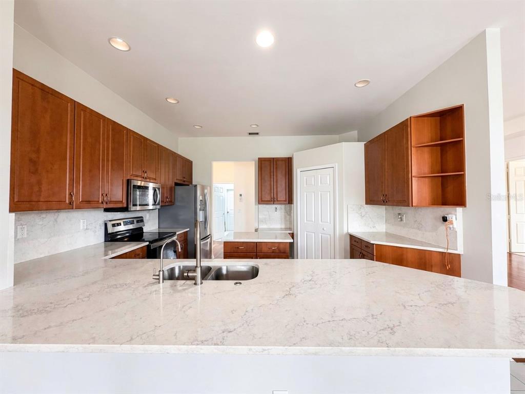 A kitchen with wood cabinets, white marble-look countertops, and stainless steel appliances — 4775 8TH STREET NE, NAPLES, FL