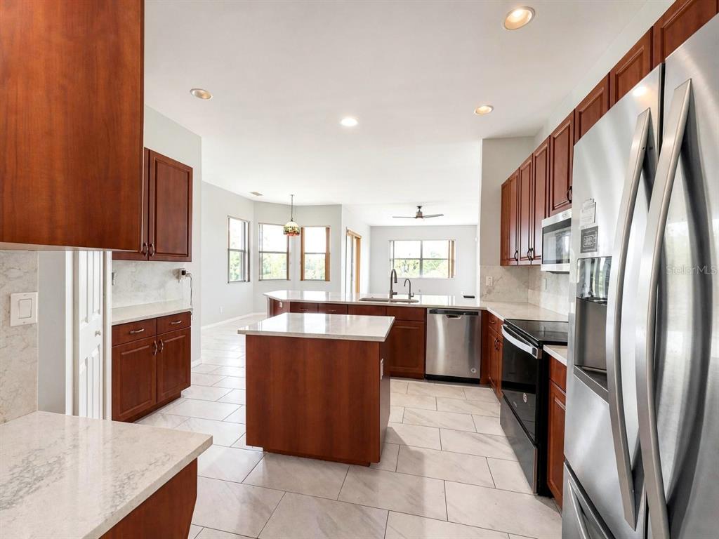A kitchen with wood cabinets, stainless steel appliances, and a central island on tile floors — 4775 8TH STREET NE, NAPLES, FL