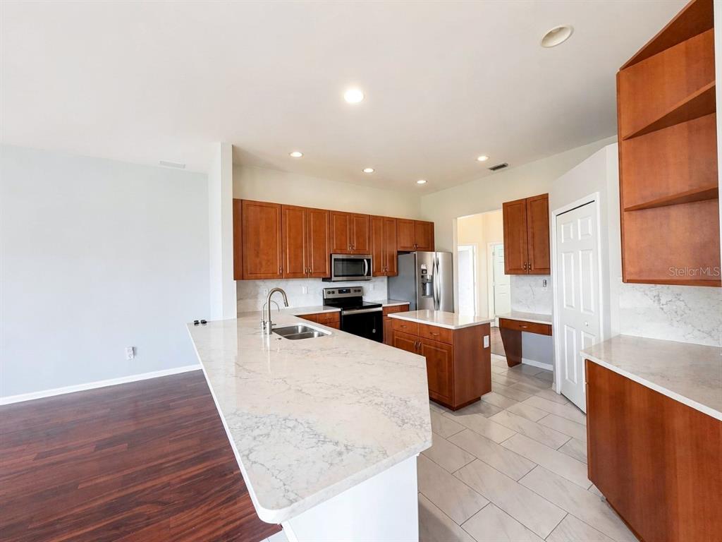 A kitchen features cherry wood cabinets, white quartz countertops, and a large center island — 4775 8TH STREET NE, NAPLES, FL