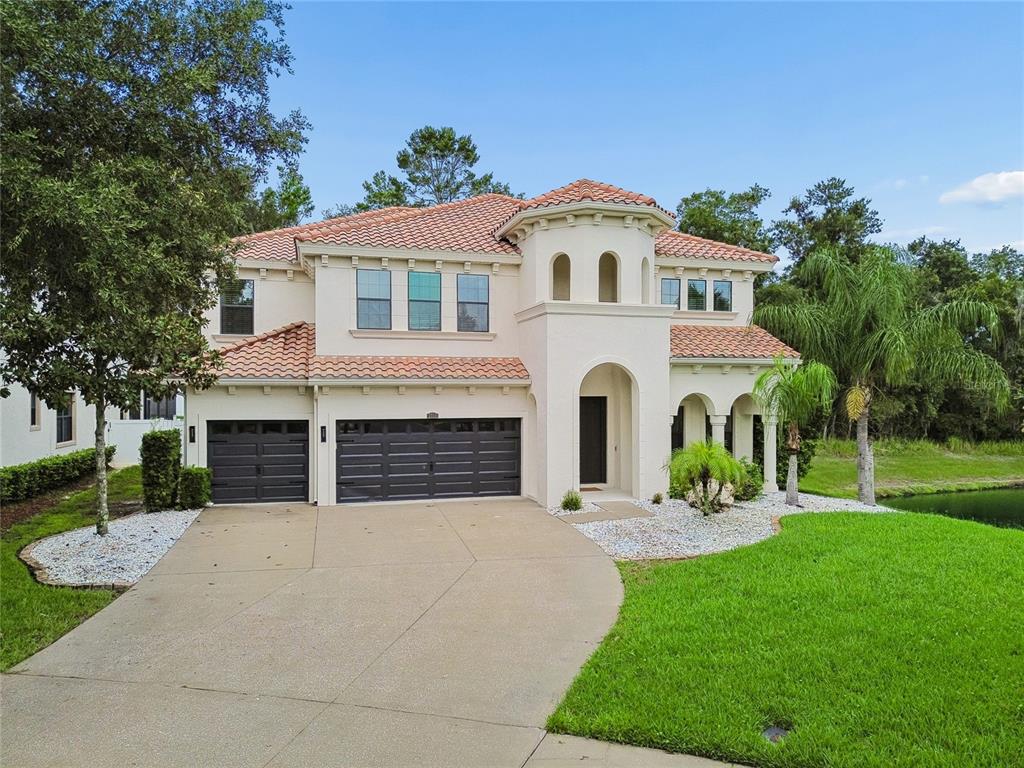 A two-story Mediterranean-style house with a stucco exterior, tile roof, and a three-car garage — 2719 CALVANO DRIVE, LAND O LAKES, FL