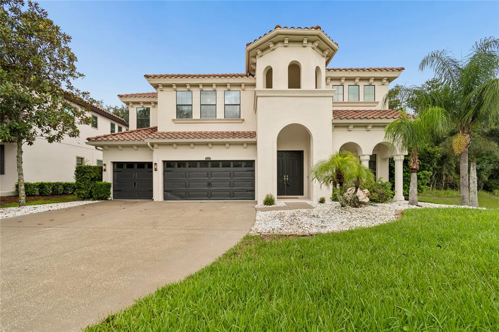 A two-story Mediterranean-style house with a tile roof, stucco exterior, and a three-car garage — 2719 CALVANO DRIVE, LAND O LAKES, FL