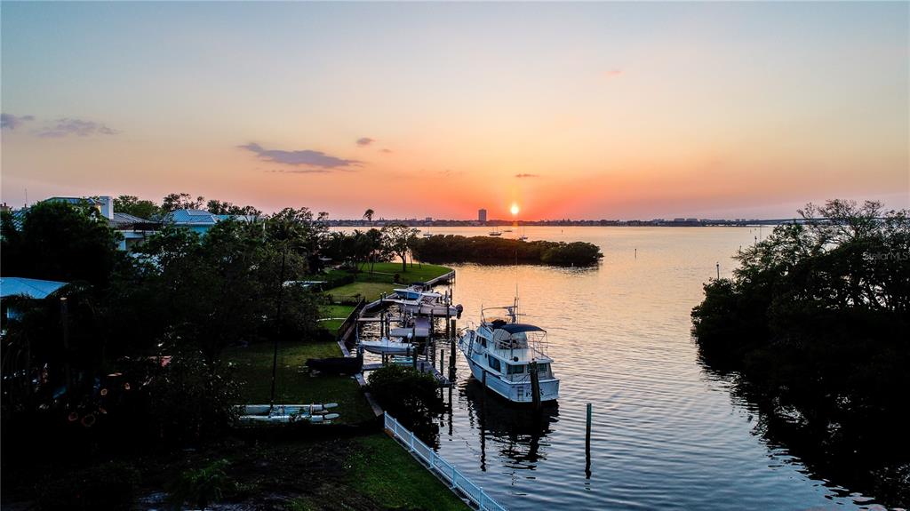 An aerial view of a sunset over a canal with a boat docked at a pier — 1521 BAY POINT DRIVE, SARASOTA, FL