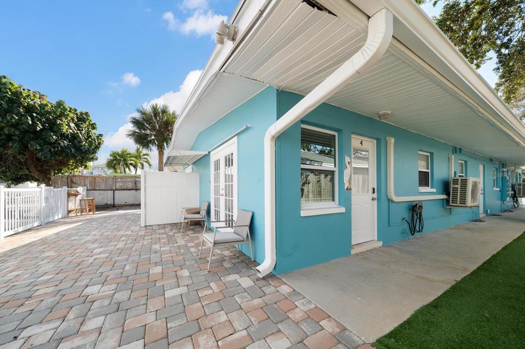A bright blue exterior wall features a white door, windows, and a paved patio area — 711 E GULF BOULEVARD, INDIAN ROCKS BEACH, FL