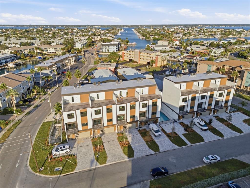 An aerial view shows a coastal neighborhood with multi-story apartment buildings, canals, and boat docks — 11605 1ST STREET E UNIT B3, TREASURE ISLAND, FL