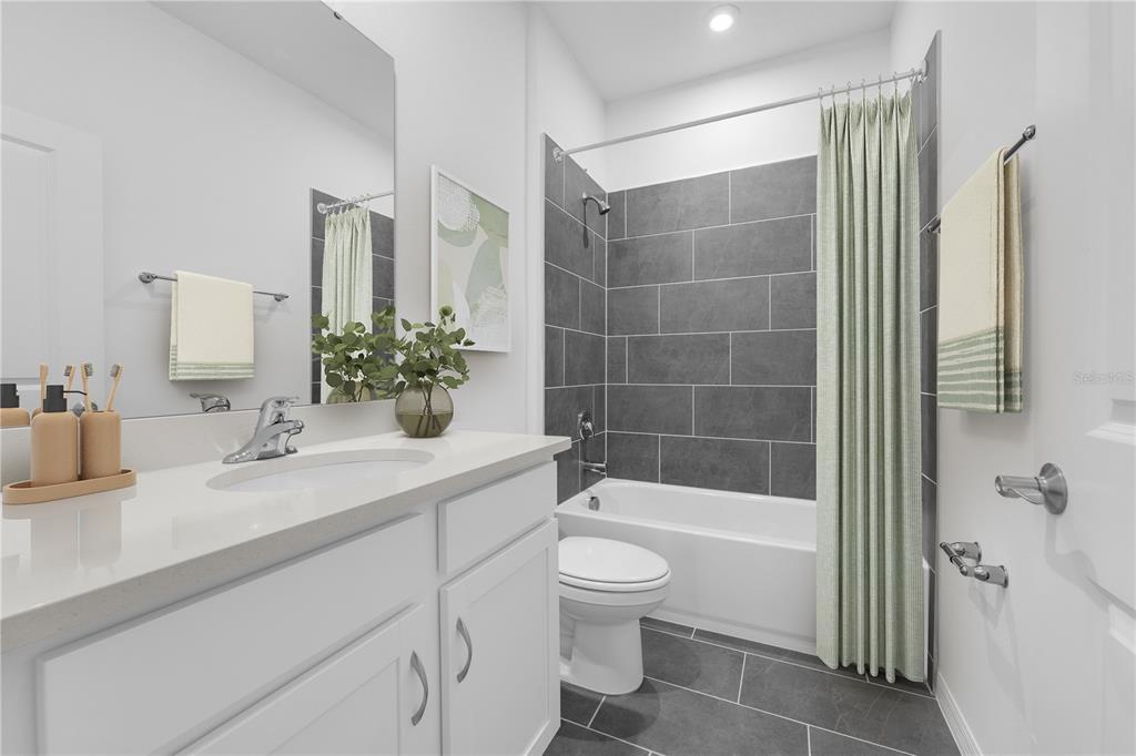 A bathroom features a white vanity, a toilet, and a tub with gray tile walls — 1075 CONNOLLY LANE, PALM BAY, FL