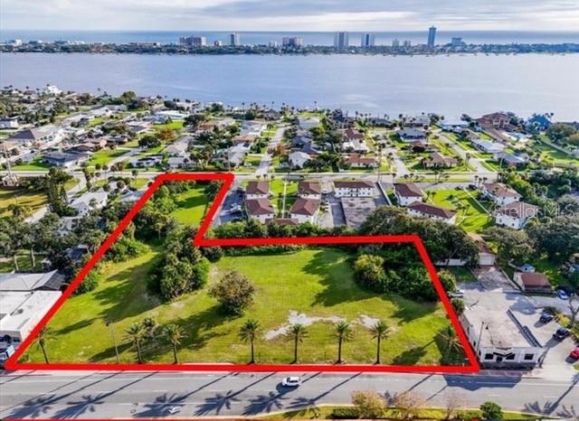 An aerial view shows a vacant, grass-covered lot outlined in red near a waterfront — 1745 S RIDGEWOOD AVENUE, SOUTH DAYTONA, FL