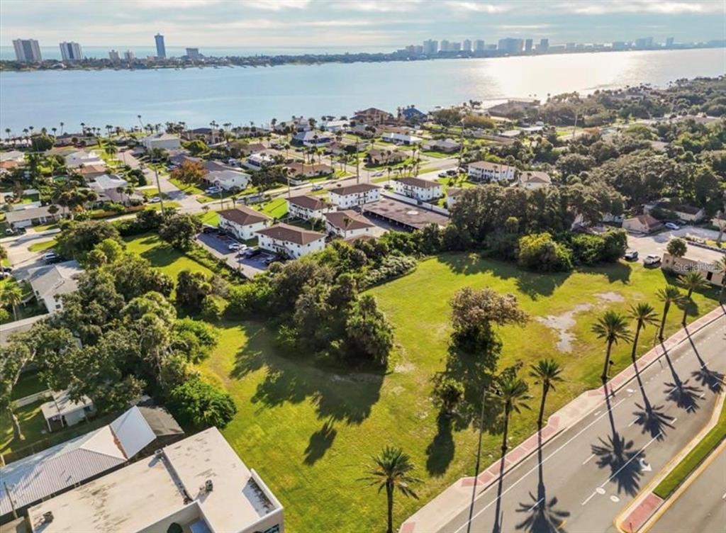 An aerial view shows a large, grassy vacant lot bordered by a road and residential buildings — 1745 S RIDGEWOOD AVENUE, SOUTH DAYTONA, FL