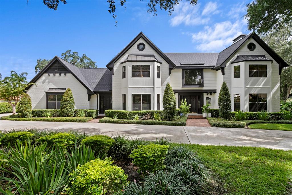 A two-story white brick house with a dark roof and a large concrete driveway — 1001 BAJADA DE AVILA, TAMPA, FL
