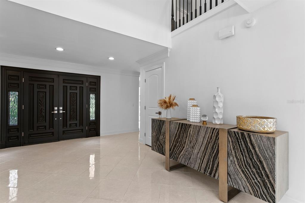 A bright foyer features a dark double door, light tile flooring, and a modern console table — 1001 BAJADA DE AVILA, TAMPA, FL