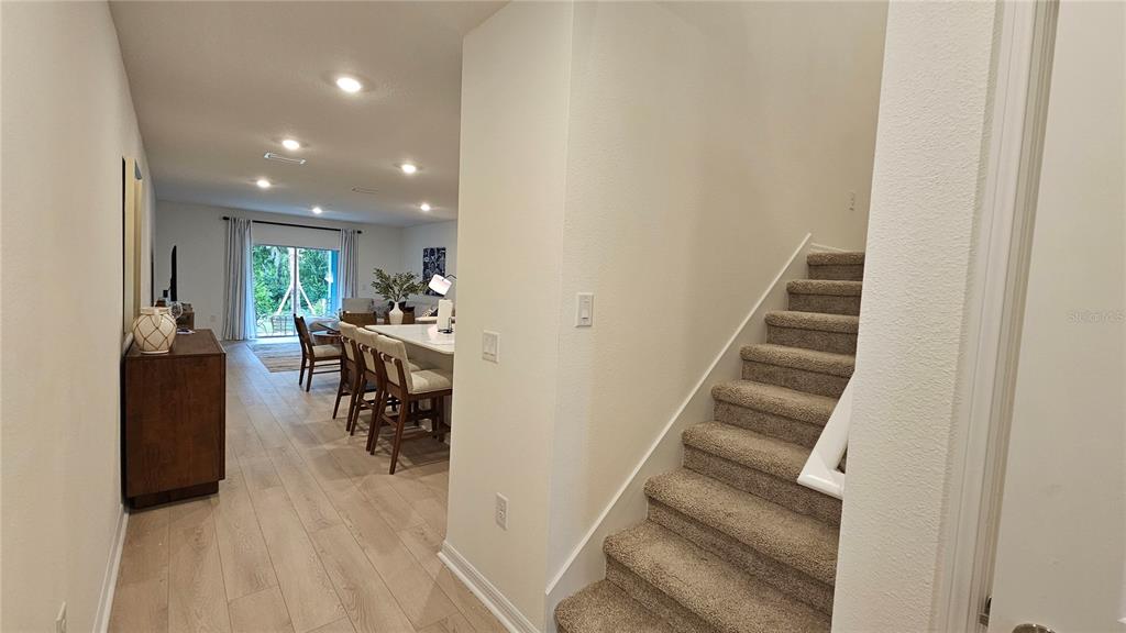A carpeted staircase leads upstairs next to an open-concept kitchen and living area — 19912 MADERA CIRCLE, VENICE, FL