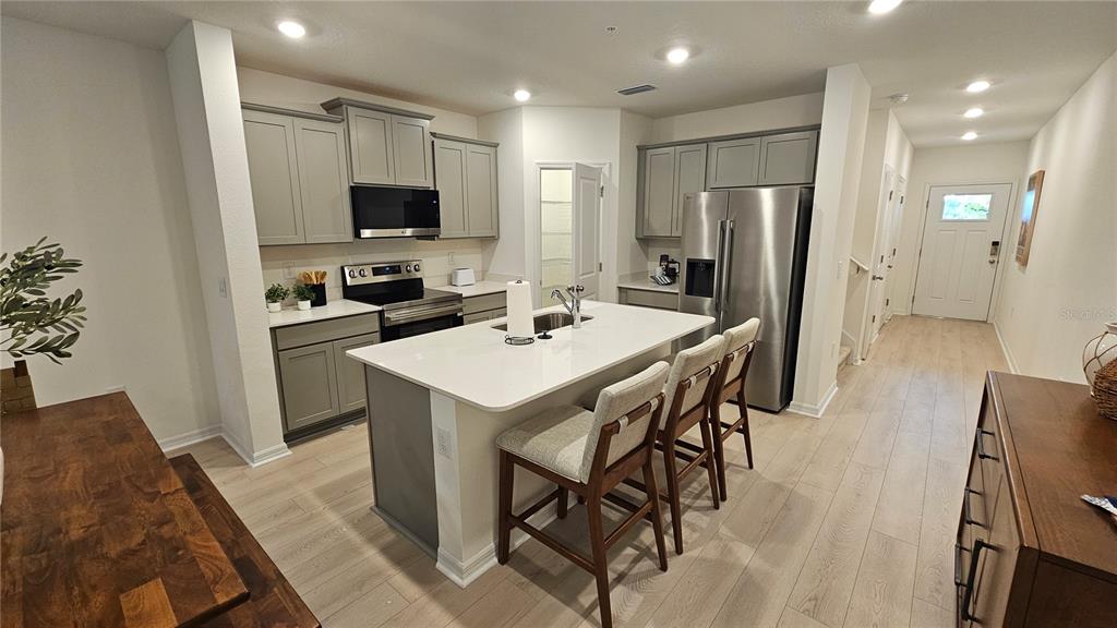 A modern kitchen features gray cabinets, a white quartz island, and stainless steel appliances — 19912 MADERA CIRCLE, VENICE, FL