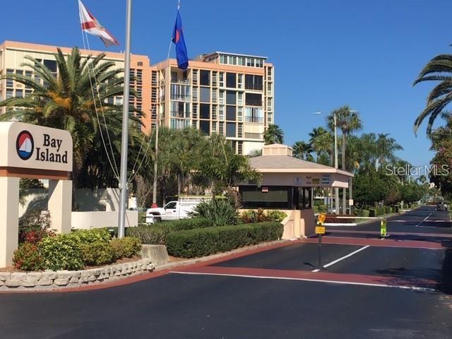The entrance to the Bay Island community features a guardhouse, signage, and palm trees — 7625 SUN ISLAND DRIVE S UNIT 202, SOUTH PASADENA, FL