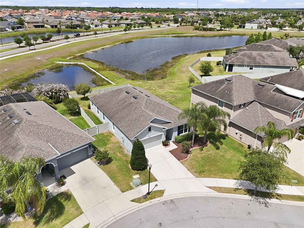 An aerial view shows suburban houses with gray roofs, driveways, and lawns near a retention pond — 11908 GREENCHOP PLACE, RIVERVIEW, FL