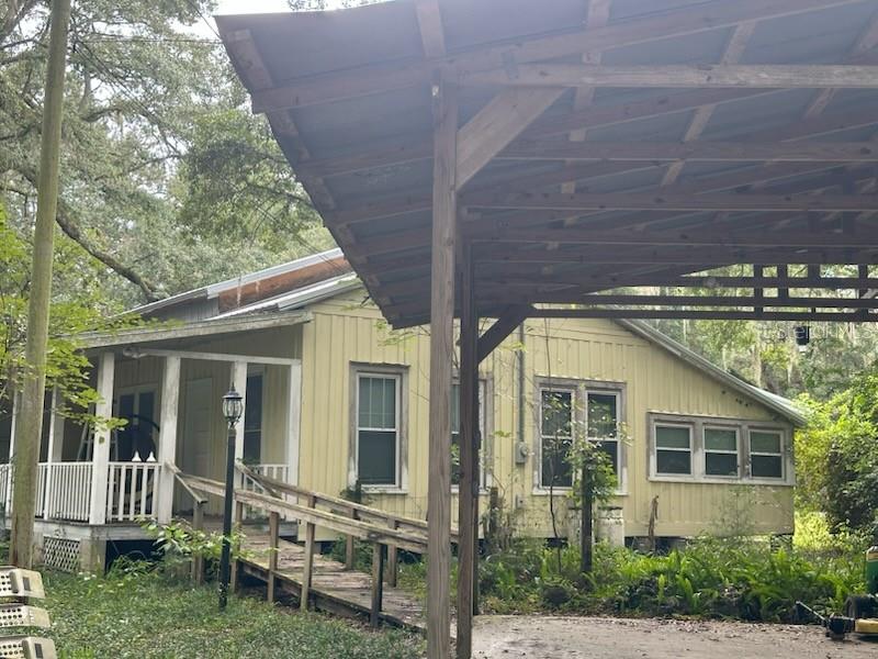 A yellow house with a wooden ramp leading to a porch and a metal carport — 5040 SE 3RD LANE, TRENTON, FL