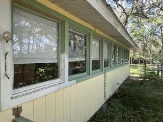 An exterior view of a house with yellow siding and a row of green-framed windows — 5040 SE 3RD LANE, TRENTON, FL