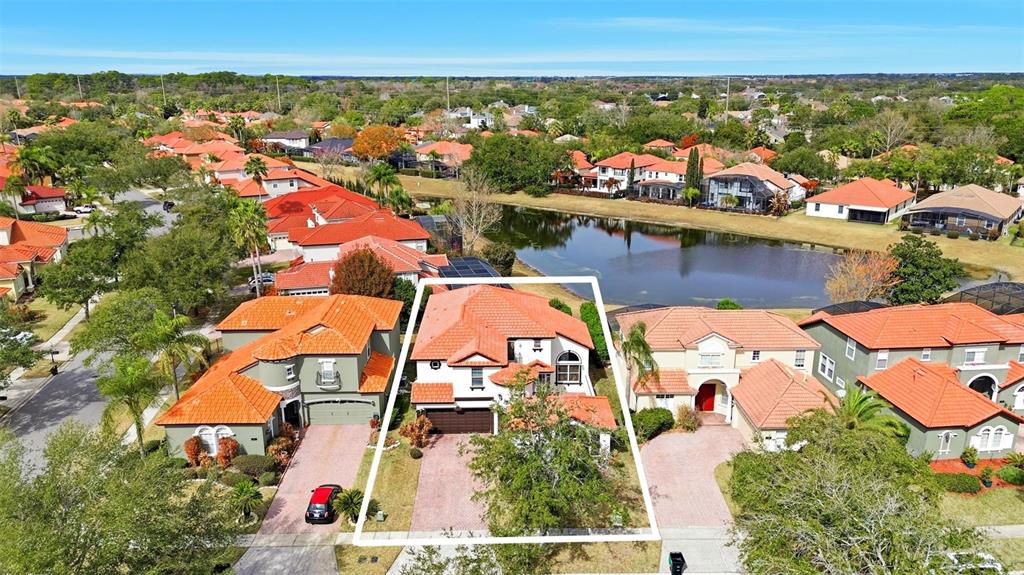 An aerial view shows a suburban house with a red tile roof near a lake — 910 LASCALA DRIVE, WINDERMERE, FL