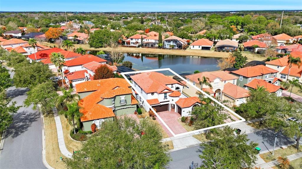A paved patio features a dining set with red chairs and a small balcony above — 910 LASCALA DRIVE, WINDERMERE, FL