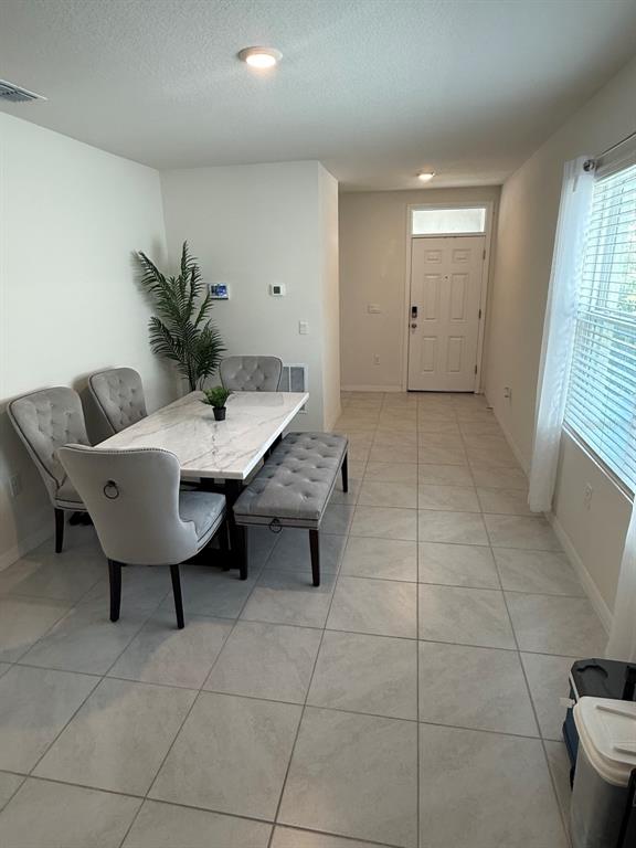 A dining area features a marble-topped table, upholstered chairs, a bench, and light tile flooring — 6772 HUNTLEIGH HAMMOCK RD, HARMONY, FL