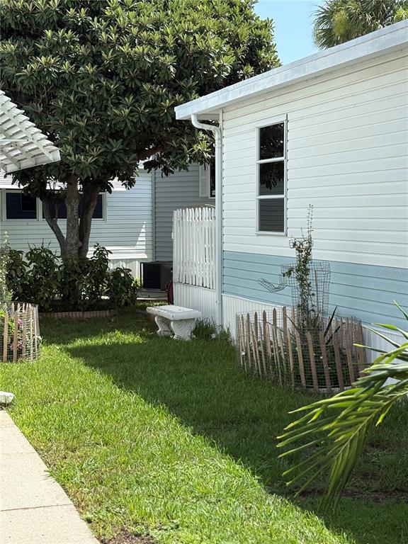The exterior of a mobile home features light blue and white siding with a small garden — 9000 US HIGHWAY 192 UNIT 565, CLERMONT, FL