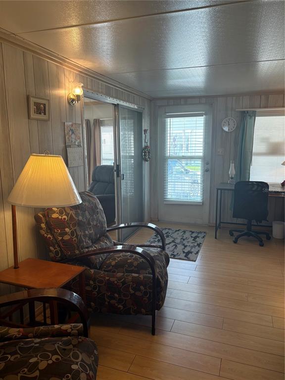 A living room with wood-paneled walls, light wood flooring, a patterned armchair, and a desk area — 9000 US HIGHWAY 192 UNIT 565, CLERMONT, FL