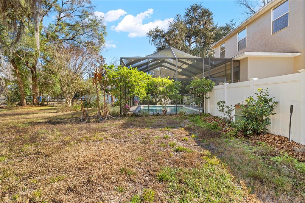 A backyard features a screened-in swimming pool, a white vinyl fence, and mature trees — SHOREWOOD DRIVE, DADE CITY, FL