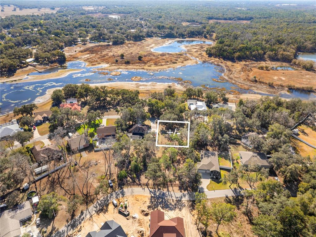 An aerial view shows a residential neighborhood with a highlighted vacant lot near a lake — SHOREWOOD DRIVE, DADE CITY, FL